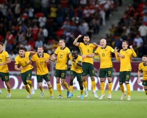 The Australian players react after winning the penalty shootout against Peru in Doha yesterday to...
