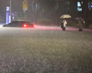 Men watch a vehicle abandoned in floodwaters during heavy rain in Seoul, South Korea, this week....
