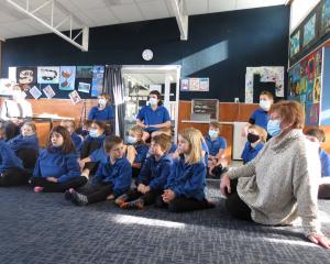 Millers Flat School principal Hilary Spedding sits with her pupils as they listen to local author...