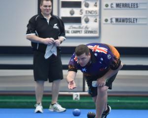 Australian representative Connor Biddle sends down his bowl in front of New Zealand opponent Ross...