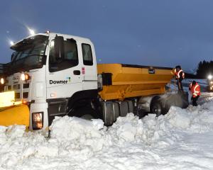 Downer workers (above) dig out a stranded snow plough on State Highway 87 yesterday morning....