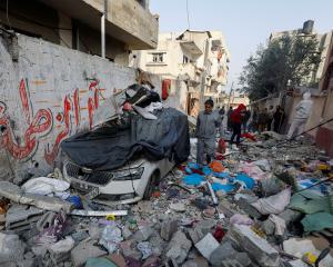 Palestinians inspect the site of an Israeli strike on a house in Rafah in the southern Gaza Strip...