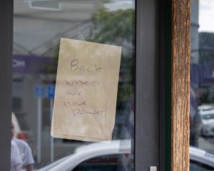 A sign on a shop window in Alexandra shows customers it is closed due to the power outage,...