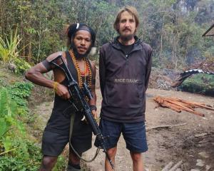 New Zealand pilot Phillip Mehrtens stands with a West Papua National Liberation Army soldier,...