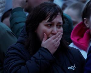 A woman reacts in front of a makeshift memorial to the victims of a shooting attack set up...