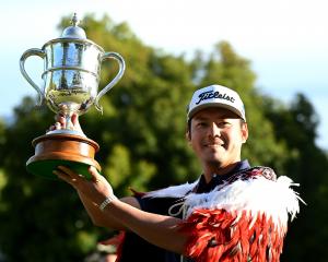 Takahiro Hataji, of Japan, dressed in the winner’s Maori cloak, celebrates with the trophy after...