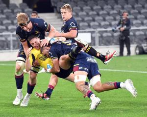 Highlanders forwards Max Hicks (right) and Fabian Holland clear out Hurricanes halfback Cam...