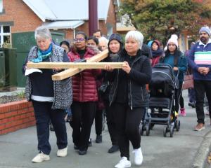 Women take over the carrying the cross during the Good Friday Cross Walk from Wachner Pl in Esk...