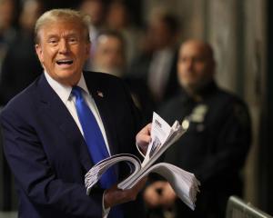Donald Trump speaks to the media while holding a stack of news clippings at a New York court....