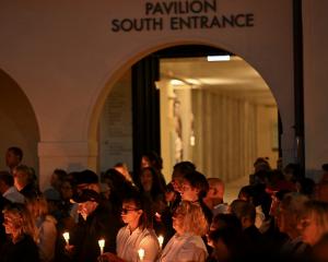 People hold candles during the a candlelight vigil in Sydney for the victims of the Bondi...