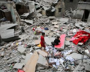 Palestinian children inspect the site of an Israeli strike on a house in Rafah, in the southern...