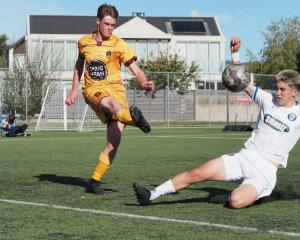Universities defender Max McGuinness makes a clearance under pressure from Christchurch United's...