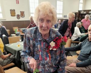 Eileen Fake cuts her 100th birthday party cake, a "House &amp; Garden" model made by Oamaru...