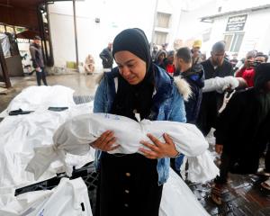 A woman holds the body of a Palestinian child killed in an Israeli strike at Abu Yousef al-Najjar...