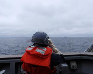 A Taiwanese sailor aboard a Taiwan Navy vessel looks towards a Chinese warship while navigating...