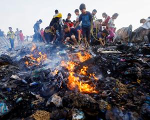 Palestinians search for food among burnt debris in the aftermath of an Israeli strike on an area...