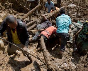 People clear an area at the site of a landslide in Papua New Guinea's Yambali village earlier...