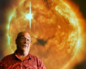 University of Otago physics Prof Craig Rodger in front of an image of a coronal mass ejection ...