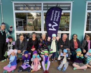 Women Helping Ōtepoti members and friends mix with Karitāne School pupils who are wearing knitted...