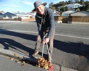 Douglas Cottages resident Russell Richards sweeps the path and surrounding areas free of autumn...