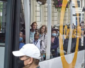 Cruise ship passengers line up to board a bus in Port Chalmers’ George St during the 2022-23...
