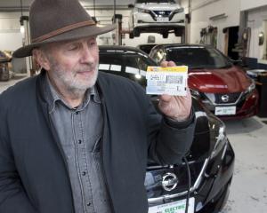 Alistair Gilmour displays a road-user charge sticker, which will be required for all electric...