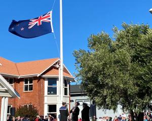 A colour party from HMNZS Toroa raises the Anzac Remembrance New Zealand flag at the commencement...