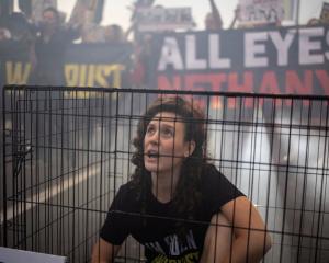 A woman sits in a cage as supporters and families of hostages, who were kidnapped during the...