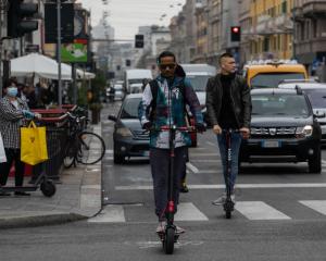 Two men ride their e-scooters through the traffic in Milan. Photo: Getty Images