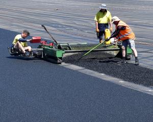 Poligras contractors spread a thin layer of rubber underlay in preparation for an Olympic Games...