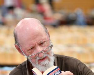 Regent Theatre 24-Hour Book Sale volunteer Brian Nicholls gets lost in the words while setting up...