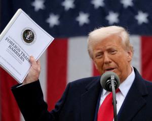 US President Donald Trump holding the "Foreign Trade Barriers" document as he delivers remarks on...