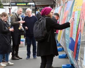 People place adhesive dots on a poster about South Dunedin to indicate areas of concern, at a...