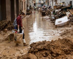 A woman walks through mud in the street after heavy rain and flooding hit large parts of Valencia...