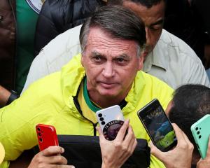 Former Brazilian president Jair Bolsonaro looks up as he greets his supporters, at a...