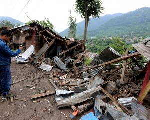 A man uses his mobile phone to film debris of shops damaged by cross-border shelling in Lagama...