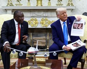 US President Donald Trump shows alleged news reports in a meeting with South African President...