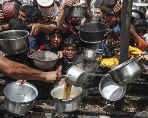 Hungry Palestinians wait to receive meals distributed by charity organisation in Jabalia Refugee...
