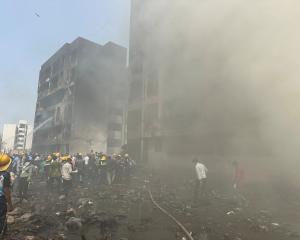 Rescue team members work as smoke rises at the site where an Air India plane crashed in Ahmedabad...