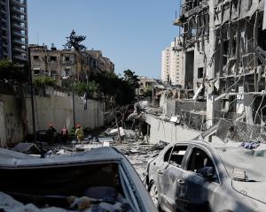 Emergency personnel work at an impact site following a missile strike from Iran on Israel, in...