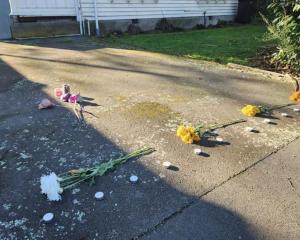 Flowers and candles laid on the driveway of a property on Gracefield Ave, where police found...