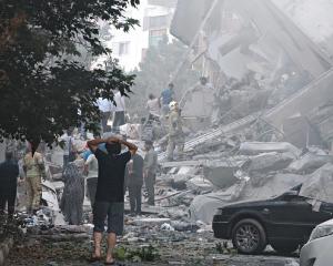 People look over damage to buildings in Nobonyad Square following Israeli airstrikes in Tehran,...