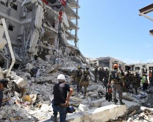 Rescue teams inspect a damaged building following a strike by an Iranian ballistic missile in Bat...