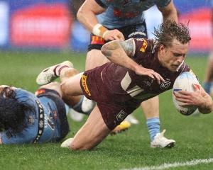 Maroons captain Cameron Munster scores in the tackle of Blues player Jarome Luai in the second...