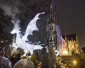 A glowing dragon exhales a smoke cloud over visitors eagerly waiting to be let into the Dunedin...