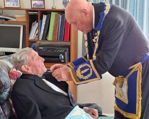 Junior grand warden Paul Johnston pins a 60-year service bar on to past master Owen Soal. PHOTO:...