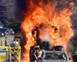 A hedge-cutting tractor is engulfed in flames in Three Mile Hill Rd yesterday. Photos: Stephen...