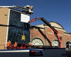 Construction workers secure a feature panel to the side of the Otago Regional Council’s new...