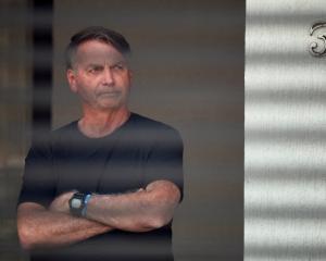 Brazil’s former president Jair Bolsonaro stands at his home while under house arrest. PHOTO:...