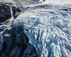 A drone view shows water from melting ice running down the side of the Turtmann glacier on a warm...